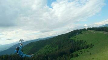 Unusual view of a woman riding a zip line among the mountains. Fast and maneuverable flight around a person video