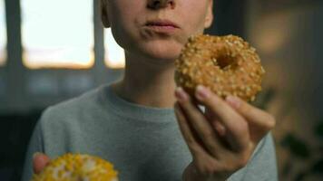 Binge eating concept. Caucasian woman with eating disorder eating two donuts quickly and at the same time video