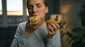 Binge eating concept. Caucasian woman with eating disorder eating two donuts quickly and at the same time video