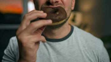 Man hastily eating sweet chocolate donut. Close-up video