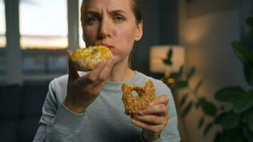 Saufgelage Essen Konzept. kaukasisch Frau mit Essen Störung Essen zwei Donuts schnell und beim das gleich Zeit video