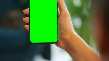 vrouw Bij huis gebruik makend van smartphone met groen mock-up scherm in verticaal modus. meisje browsen internetten, aan het kijken inhoud video