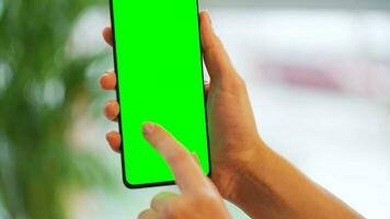 vrouw Bij huis gebruik makend van smartphone met groen mock-up scherm in verticaal modus. meisje browsen internetten, aan het kijken inhoud video