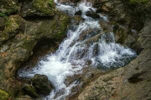 escénico ver de increíble agua corriente Entre rocas cerca arriba foto