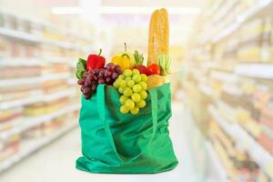 Shopping bag with fruits and vegetables in supermarket grocery store blurred background photo