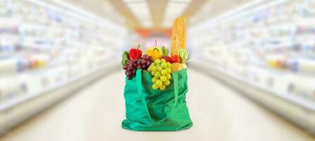 Shopping bag with fruits and vegetables in supermarket grocery store blurred background photo