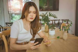 Young woman using credit card and mobile phone for online shopping in cafe, coworking space or coffee shop. Technology money wallet, online payment concept, credit card mockup. Safe mobile banking photo