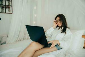 retrato de cansado hermosa mujer teniendo dolor de cabeza a hogar después trabajando con ordenador portátil computadora para un largo tiempo. utilizando cuaderno y grave. pensando acerca de camino a completo. salud - tecnología concepto. foto