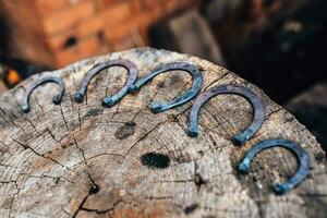 Hand forged horseshoes on a tree stump - the craft of an old fashioned blacksmith photo