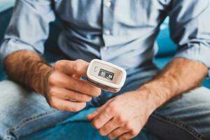 Measurement of oxygen level and pulse rate with a portable pulse oximeter - a man monitors his health - saturation 95 pulse 84 photo