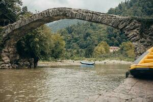 Ancient stone arch bridge over the river in the mountains - architecture and construction of the middle ages photo