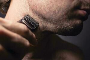 Caucasian man shaves his neck with an electric trimmer leaving the stubble necessary length photo