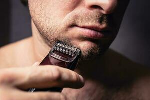 Close up modeling a beard and bristles with an electric shaving trimmer photo