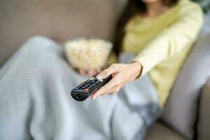 Asian woman Watching smart TV and using remote controller Hand holding television audio remote control at home with the remote control television photo