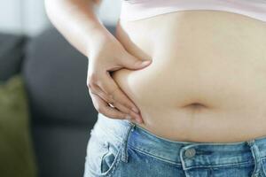 Obese Woman with fat upset about her belly. Overweight woman touching his fat belly and want to lose weight. Fat woman with tight clothing worried about weight diet lifestyle concept photo