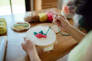 puñetazo aguja. asiático mujer haciendo hecho a mano pasatiempo tejido de punto en estudio taller. diseñador lugar de trabajo hecho a mano arte proyecto bricolaje bordado concepto. foto