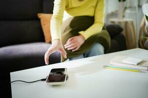 Charging mobile phone battery with wireless charging device in the table. Smartphone charging on a charging pad. Mobile phone near wireless charger Modern lifestyle technology concept. photo