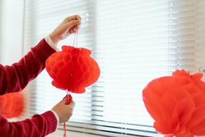 Asian Woman holding red Chinese new year lantern while decorated flat putting traditional pendant to the Chinese New Year Celebrations for good luck. chinese word means blessing. photo