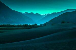 Beautiful desert and sand landscape with stunning mountain background on blue and green sky. photo