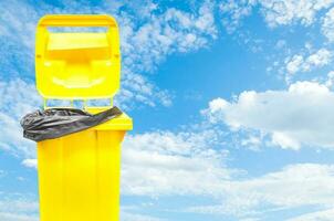 yellow bin on blue sky background photo