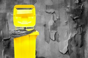 yellow bin on dark old broke wall background photo