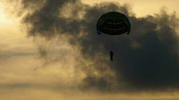 silueta paracaídas volador en contra nublado puesta de sol cielo. extremo Deportes, parapente recreativo aventuras deporte video