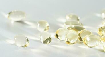 Vitamin D yellow supplement gel capsules, Fish Oil Omega 3 on white background, macro shot photo