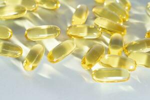 Fish Oil Omega 3 on white background, vitamin D yellow supplement gel capsules, macro shot photo