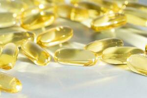 Fish Oil Omega 3 on white background, vitamin D yellow supplement gel capsules, macro shot photo