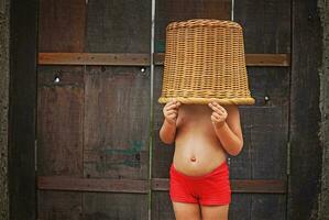 Cute and funny little girl with basket on her head photo