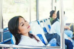 sobrecargado de trabajo asiático oficina trabajador dormido en un autobús foto