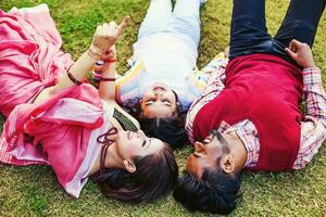 Beautiful Indian family  in the park, pointing at something aBeautiful Indian family lying down  in the park, pointing at something and looking upnd looking up photo