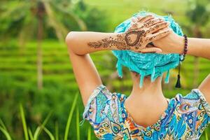 rare view of a woman looking at a rice field with mehendi tattoo on her hand photo