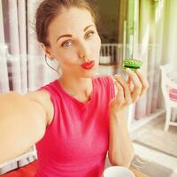 woman looking at macaroon she's going to eat. Lovely color combination of pink and green photo