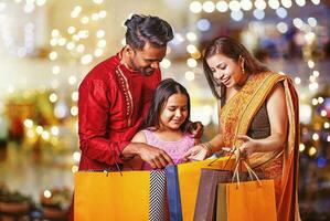 hermosa indio familia con pequeño hija compras y acecho su compras y regalos en el centro comercial en diwali hora foto