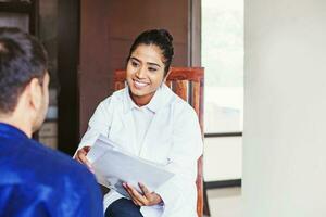 Young female Indian doctor consulting a patient while holding medical reports in her hands photo