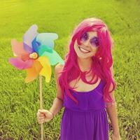 optimistic young woman wearing pink wig posing outdoors photo