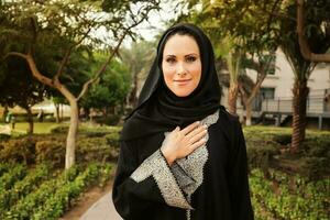 young muslim woman wearing hijab greeting at camera photo