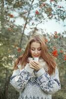 beautiful woman drinking tea from thermos in the forest photo