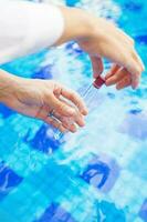 Analyzing of a water from swimming pool, taking water sample to a flask photo