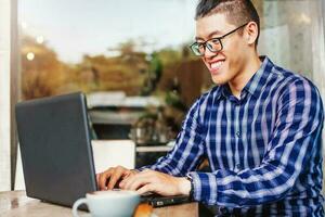 Happy Chinese young man using laptop computer photo