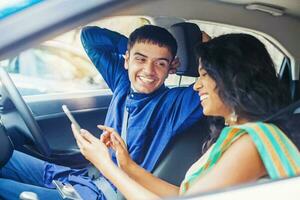 hermosa indio Pareja en un coche utilizando móvil teléfono a plan su viaje en línea foto