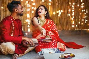 Beautiful Hindu Indian couple in red ethnic clothes praying with hawan on first day of Navratri festival photo