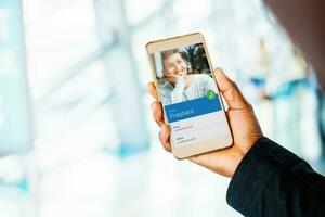 Calling a friend. Hand holding phone with video call with young indian man photo