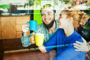 Lovely couple drinking tea together and talking. View through the glass window photo