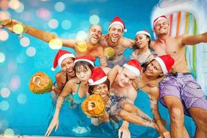 mixed raced  group of nine people celebrating christmas in a swimming pool photo