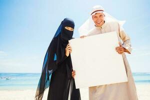 muslim couple on a beach wearing traditional dress photo