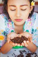 Balinese woman in traditional costume smelling coffee beans photo