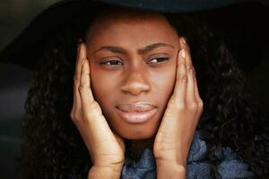 a thoughtful beautiful young African woman sitting with her face in her hands photo