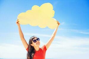 Cloud storage concept. Woman holding paper cloud icon on the beach photo